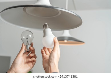 Energy saving idea: Asian people replace fluorescent light bulbs (CFL) with new LED bulbs. Female hands screw in an energy-saving LED light bulb. - Powered by Shutterstock