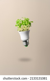 Energy saving led lamp, made with green grass flying over beige background. Ecology and Green energy concept. Eco-friendly, green power. - Shutterstock ID 2133131081