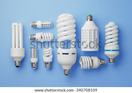 Energy saving light bulbs organized over blue background, top view.