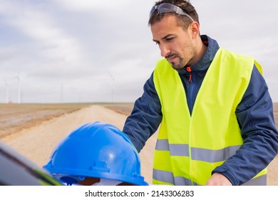 Energy Sector Worker Working On His Laptop In His Car At A Wind Farm. Renewable Energy, Clean Energy And Climate Change Concept.