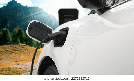 Energy sustainable car power by electro generator drive, recharge battery at charging station with mountain background for progressive travel concept. EV car in nature as symbol for clean environment. - Shutterstock ID 2272315713