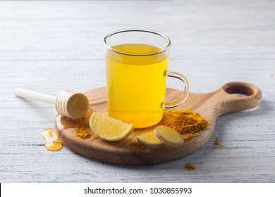 Energy tonic drink with turmeric, ginger, lemon and honey on a wooden board, selective focus - Shutterstock ID 1030855993