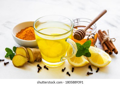Energy tonic drink with turmeric, ginger, lemon and honey on a white wooden  background