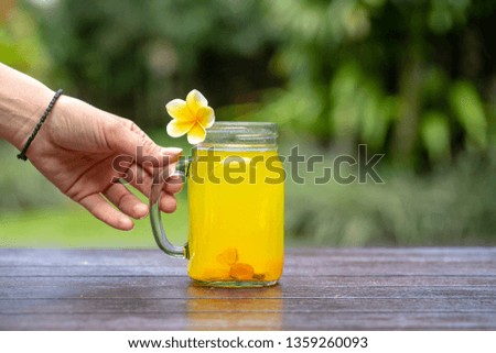 Energy tonic drink with turmeric, ginger, lemon and honey in glass mug, nature background, close up . The concept of healthy eating