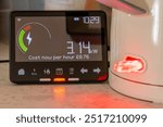 A energy use and cost concept with a smart energy meter showing the amount of energy in use next of a kettle boiling water.