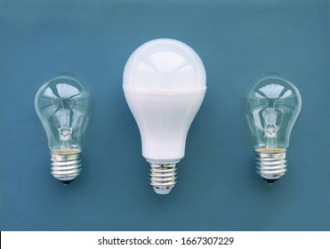 Energy-saving lamp with incandescent lamps in a row on a blue background. The concept of saving energy. Close up.