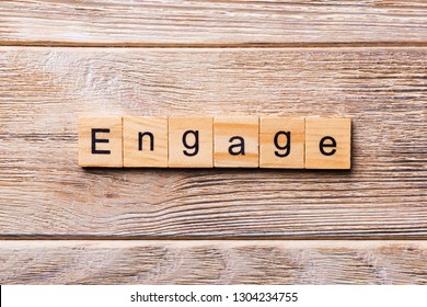 ENGAGE word written on wood block. ENGAGE text on wooden table for your desing, concept.
