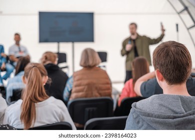 Engaged audience listening to a presenter at an informal outdoor event, focus on foreground listeners.  - Powered by Shutterstock