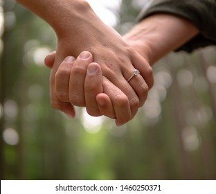 An Engaged Couple Holding Hands With A Diamond Ring On The Girls Hand