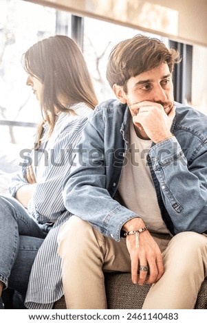 Engaged couple with relationship problems sitting on the sofa with their backs to each other after an argument, conflicts in marriage, upset couple after a dispute, making decision to break up divorce