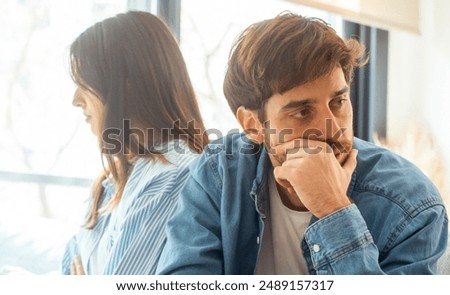 Engaged couple with relationship problems sitting on the sofa with their backs to each other after an argument, conflicts in marriage, upset couple after a dispute, making decision to break up divorce
