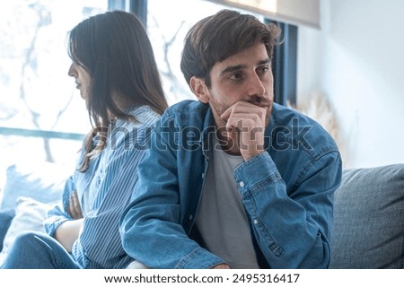 Engaged couple with relationship problems sitting on the sofa with their backs to each other after an argument, conflicts in marriage, upset couple after a dispute, making decision to break up divorce