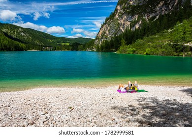 engaged couple sunbathe by the lake on a sunny day enjoying the mountain panorama - Powered by Shutterstock