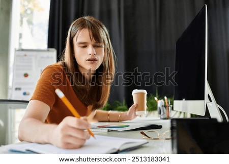 Engaged in focused work, a young non binary individual writes notes while deep in thought.