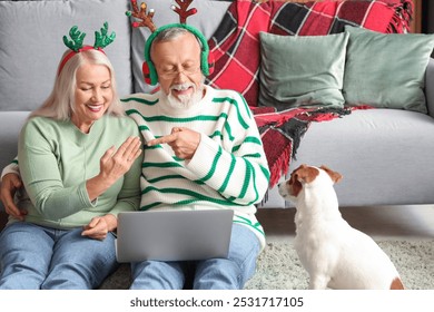 Engaged mature couple with Jack Russell terrier video chatting at home on Christmas eve - Powered by Shutterstock