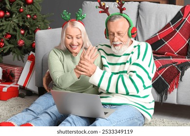 Engaged mature couple with laptop video chatting at home on Christmas eve - Powered by Shutterstock