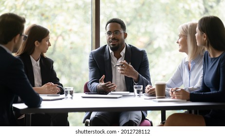Engaged Motivated African American Business Leader Talking To Team, Meeting With Employees, Managers. Corporate Coach, Mentor Training Staff. Diverse Group Discussing Work Project At Table