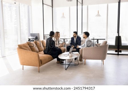 Engaged multiethnic business team sitting in circle on couch, in armchairs in office co-working space, discussing teamwork strategy, solutions for project, talking on collaboration, brainstorming