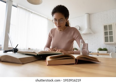 Engaged In Paperwork. Serious Young Latina Woman Post Graduate Student Sit At Desk Focused On Preparing Diploma Paper Work On Degree. Young Female Scientist In Glasses Read Books Carrying Out Research