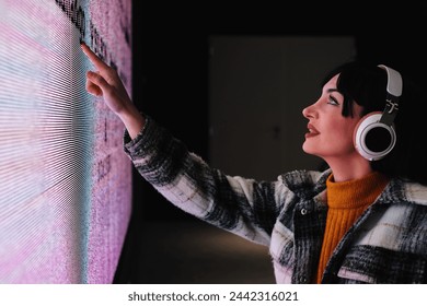 Engaged woman in wheelchair touches a dynamic digital art piece at a contemporary gallery.