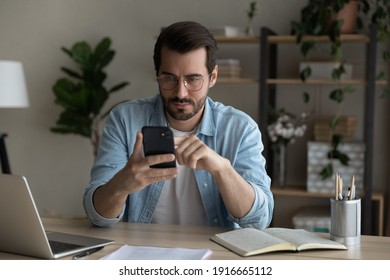 Engaged in work. Busy young man expert call client partner to discuss deal set up meeting due to free time in business schedule. Serious guy student check uncertain information online using smartphone
