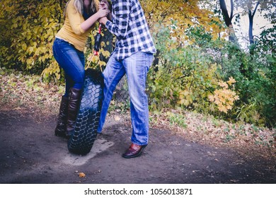 Engagement Photo Of Couple Playing On Tire Swing In Fall Weather.