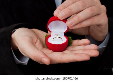 Engagement ring in hands. Man in suit holding an open box with engagement ring inside  - Powered by Shutterstock