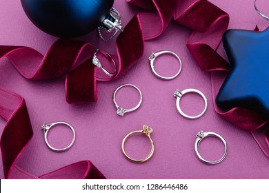 Engagement Rings With Diamonds On Purple Background With Christmas Decorations. White Gold, Silver Wedding Rings With Gemstones. Fashion Jewelry Advertising 