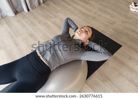 Engaging in a core workout routine with a stability ball during a bright afternoon at home