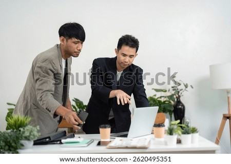 Engaging Presentation and Team Interaction. Professionals collaborating on a laptop in a modern office.