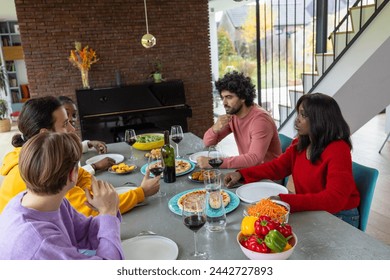 An engaging snapshot of a diverse group of friends engrossed in conversation over a delicious lunch in a stylish home setting. The table is rich with Italian-inspired dishes, and the open room is - Powered by Shutterstock