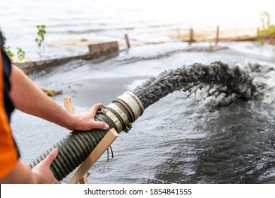 Engeneer Hold Pipe Of Power Pump Machine Pouring Mud Sludge Waste Water With Sand Silt On Ground. Sand-wash And Coast-depeening. Septic Sewage Maintenance Service. Industrial Environment Pollution