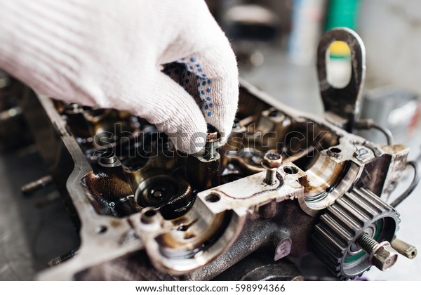 Engine crankshaft,\
valve cover, pistons. mechanic repairman at automobile car engine\
maintenance repair work