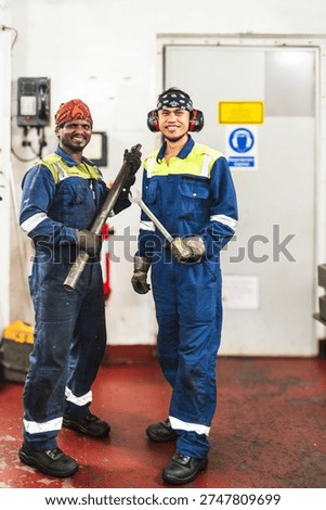 Engine department crew posing together in vessel maintenance area.