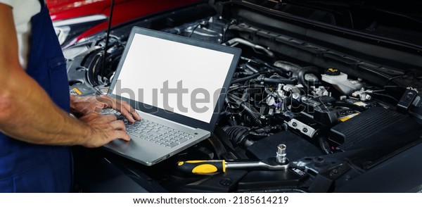 engine diagnostics - car mechanic using laptop\
computer to diagnose vehicle motor in repair shop. blank screen\
copy space