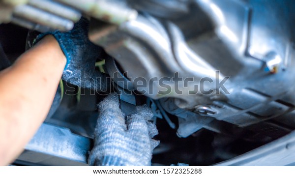 Engine
oil and car maintenance service concept - Blurred mechanical hand
with engine oil filter replacement service  in car garage and copy
space, use for car maintenance service
content.