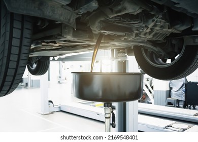 Engine oil change in car service. Auto is on hydraulic lift in garage workshop, process of draining old dark used oil - Shutterstock ID 2169548401