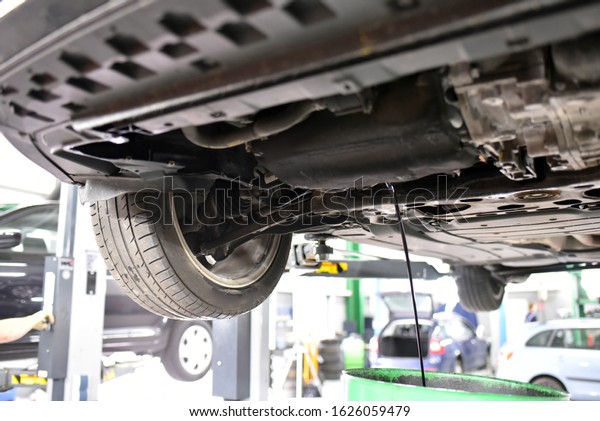 engine oil change in a garage - vehicle on\
the lifting platform - draining of used oil\
