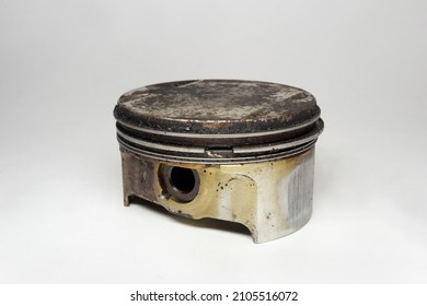 engine piston with black sludge of deposit formations on flat head surface. gas-tight seal compression rings between the ring lands, showing hole for wrist pin