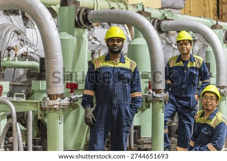 Engine room team posing close to main propulsion system.