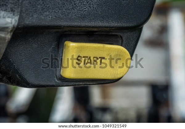 Engine Start Button. Old and dirty.\
pushed action start yellow button, motivation concept. car, moped\
and motorcycle interior, key, start&stop.\
