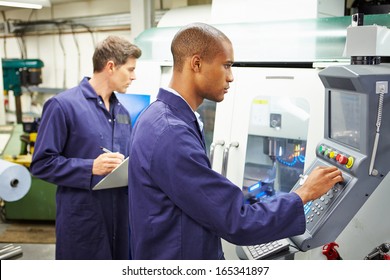 Engineer And Apprentice Using Automated Milling Machine