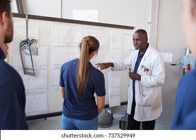 Engineer with apprentice at white board in front of group