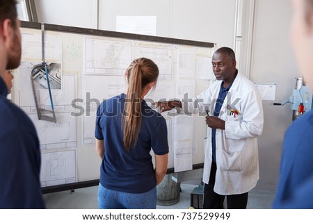 Engineer with apprentice at white board in front of group