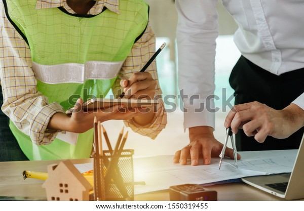 engineer and architect team drawing and planning\
about building plan with blueprint, construction tools on\
conference table at construction site, contractor, engineering, and\
construction concept