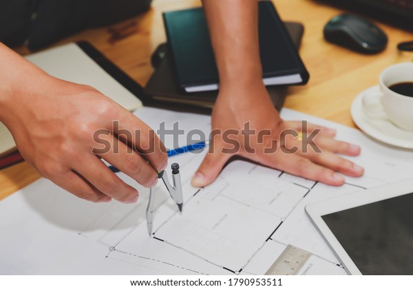 Engineer or architect using divider compass tools\
on blueprint in office on\
site.