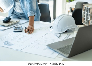Engineer architect working at desk and building model   equipments in office workplace using laptop  thinking  planning   discussing about blueprints building construction project 