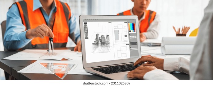 Engineer and architect working together brainstorming and designing blueprint using laptop working with architectural software for precise digital interior or structure design. Insight