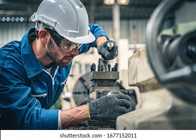 Engineer in blue jumpsuit and white hardhat operating lathe machine.  - Powered by Shutterstock