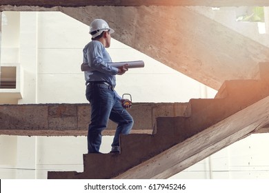 Engineer with blueprint on stairs in building construction site